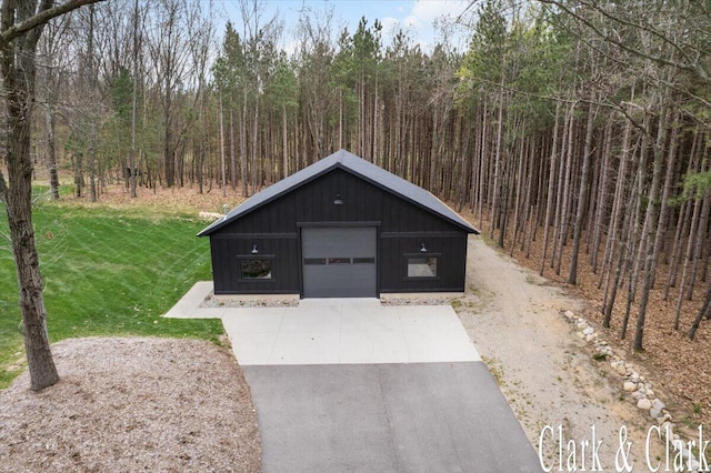 detached garage featuring driveway and a forest view