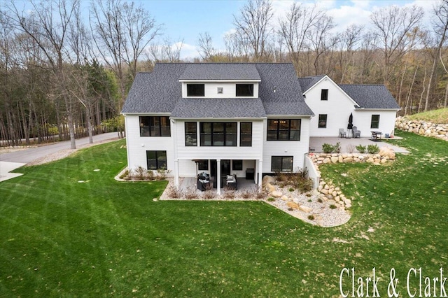back of property featuring a patio, a shingled roof, a lawn, and a sunroom