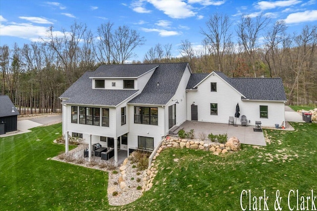 rear view of house featuring a lawn, a shingled roof, a patio area, and a sunroom
