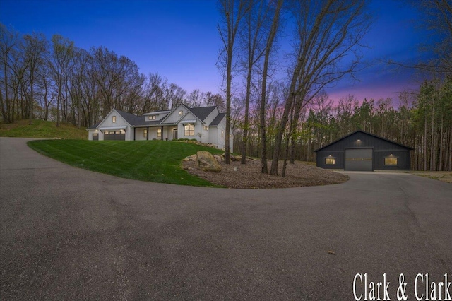 traditional home featuring a detached garage, a front yard, and aphalt driveway