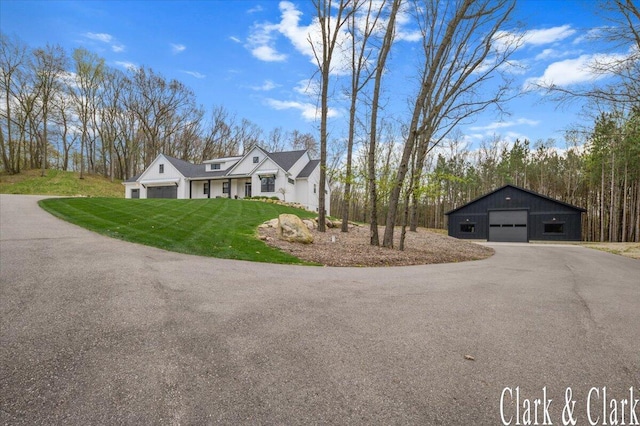 view of front of home with a garage, an outbuilding, a front lawn, and aphalt driveway