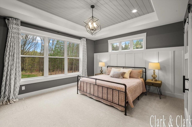 bedroom with carpet flooring, multiple windows, and a raised ceiling