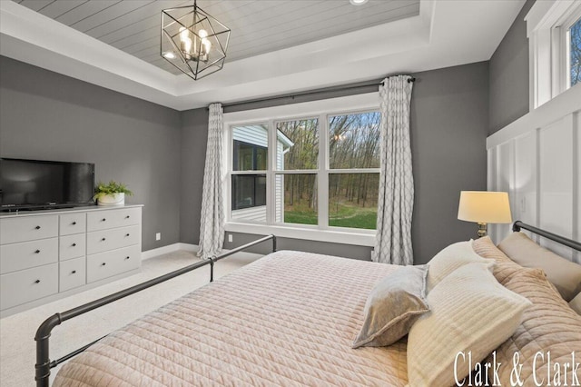 carpeted bedroom with baseboards, a notable chandelier, and a raised ceiling
