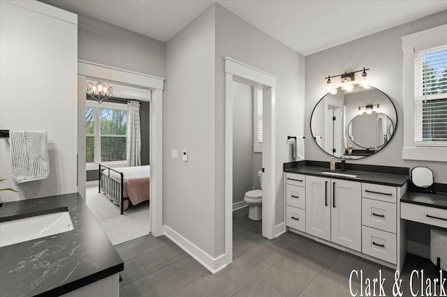 ensuite bathroom featuring plenty of natural light, tile patterned floors, toilet, and vanity