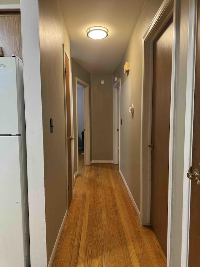 hallway featuring baseboards and light wood finished floors