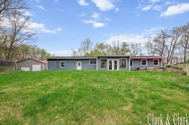 back of house featuring a lawn, a garage, an outbuilding, and french doors