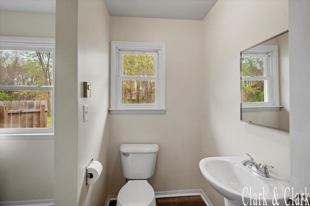 bathroom featuring toilet, baseboards, and a sink