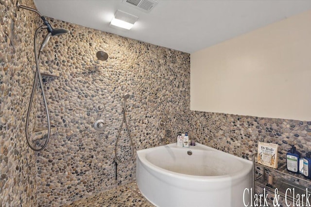 bathroom featuring a washtub, a tile shower, and visible vents