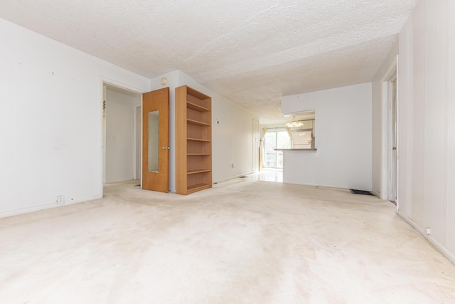 carpeted empty room with baseboards and a textured ceiling