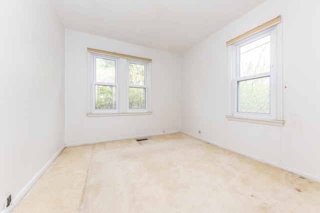 carpeted spare room featuring baseboards and visible vents