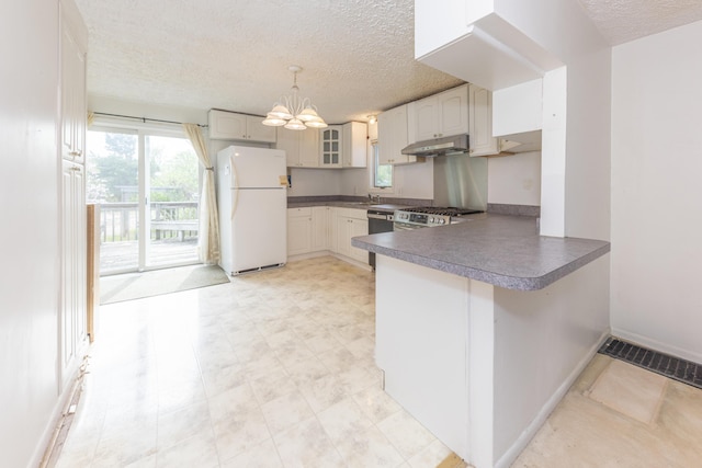 kitchen featuring freestanding refrigerator, a textured ceiling, under cabinet range hood, dishwashing machine, and a peninsula