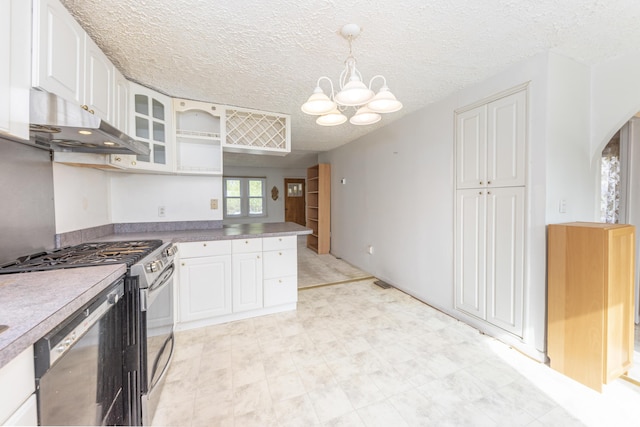 kitchen featuring glass insert cabinets, stainless steel gas range oven, an inviting chandelier, under cabinet range hood, and white cabinetry