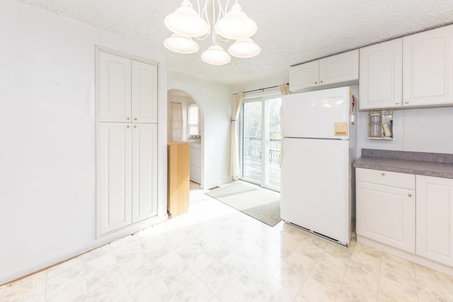 kitchen with white cabinets, arched walkways, a textured ceiling, a chandelier, and freestanding refrigerator