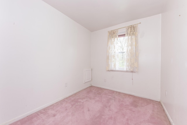 spare room with baseboards and light colored carpet