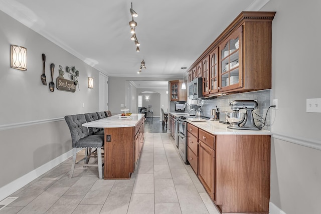 37 N Monroe St, Coldwater, MI 49036 - kitchen with appliances with stainless steel finishes, brown cabinetry, a kitchen island, and arched walkways