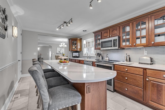 37 N Monroe St, Coldwater, MI 49036 - kitchen featuring arched walkways, light tile patterned flooring, a kitchen island, and stainless steel appliances