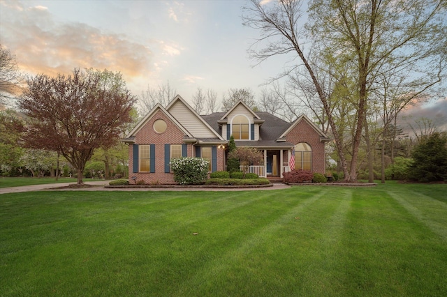 view of front facade featuring covered porch, brick siding, and a lawn