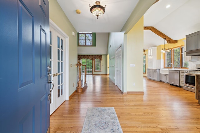 entryway with lofted ceiling, light wood-style floors, french doors, and baseboards