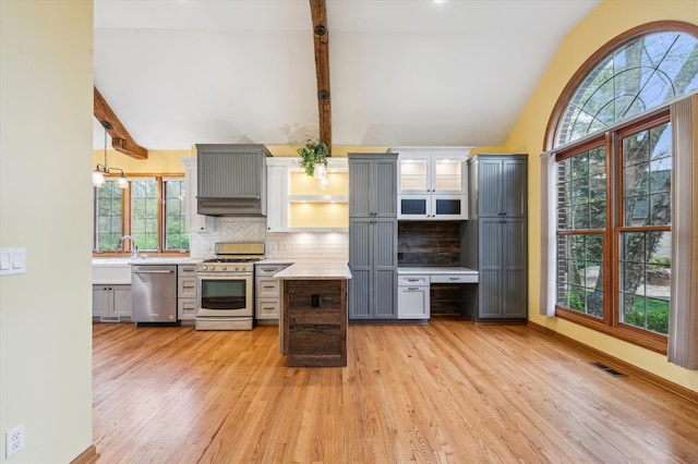 kitchen with light wood-style floors, decorative backsplash, appliances with stainless steel finishes, and vaulted ceiling with beams