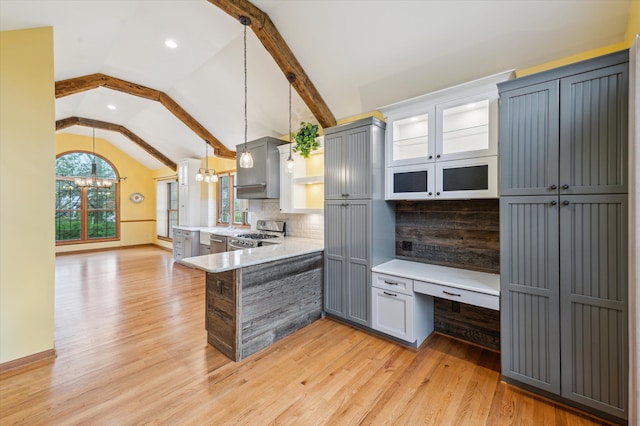 kitchen featuring a peninsula, decorative backsplash, vaulted ceiling, light wood-style floors, and appliances with stainless steel finishes