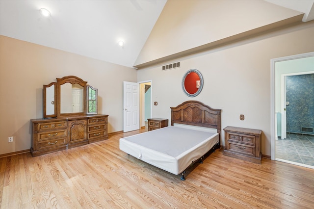 bedroom with baseboards, light wood finished floors, visible vents, and high vaulted ceiling
