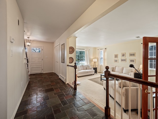 foyer entrance featuring a baseboard heating unit, baseboards, and stone tile flooring
