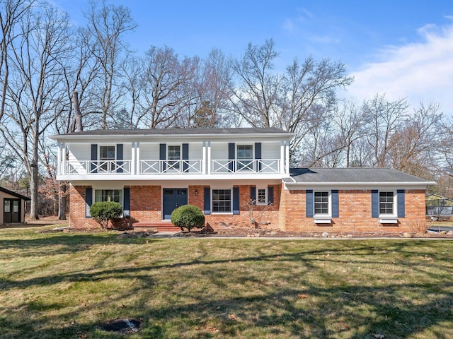 view of front facade featuring a porch, a front lawn, brick siding, and a balcony