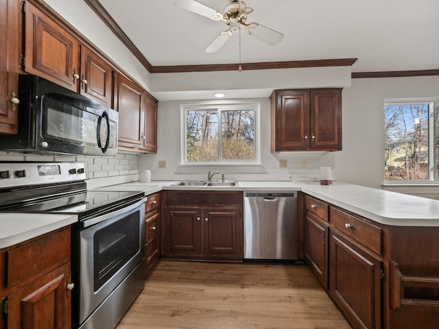 kitchen featuring a ceiling fan, a sink, a peninsula, crown molding, and stainless steel appliances