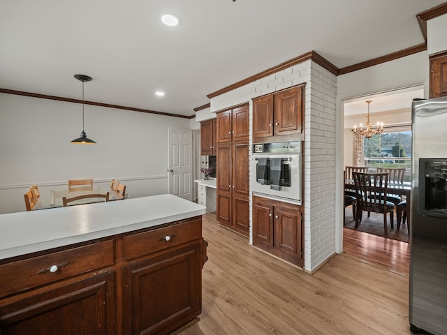 kitchen with an inviting chandelier, stainless steel fridge, crown molding, and oven