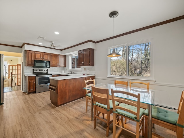 kitchen with a peninsula, a healthy amount of sunlight, visible vents, light countertops, and appliances with stainless steel finishes
