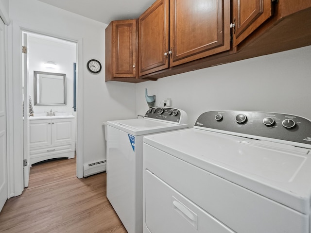 clothes washing area with a sink, cabinet space, independent washer and dryer, light wood-type flooring, and baseboard heating