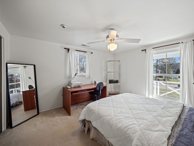 bedroom with multiple windows, visible vents, a ceiling fan, and light carpet