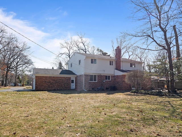 rear view of property with a chimney, brick siding, and a lawn