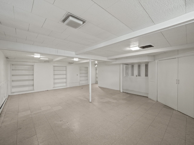 finished below grade area featuring visible vents and built in shelves