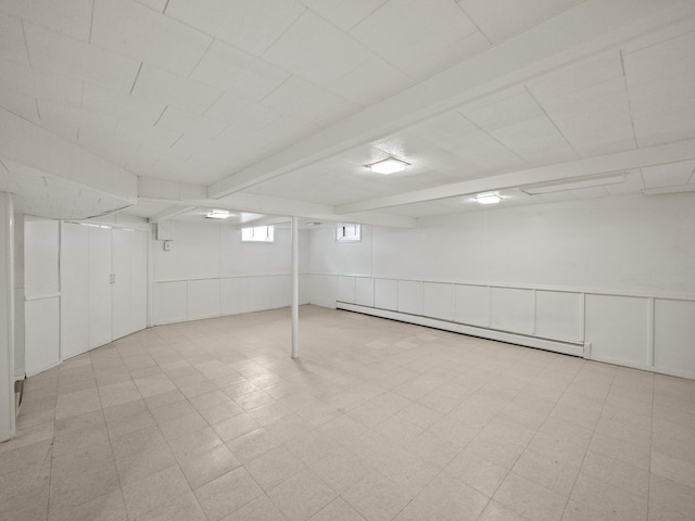 below grade area with wainscoting, a decorative wall, and baseboard heating
