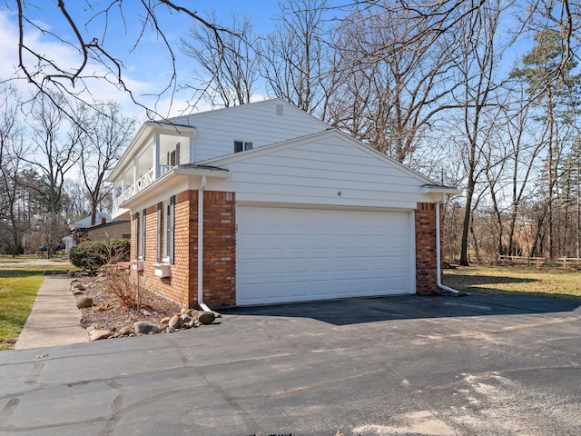 view of home's exterior featuring an attached garage, brick siding, and driveway