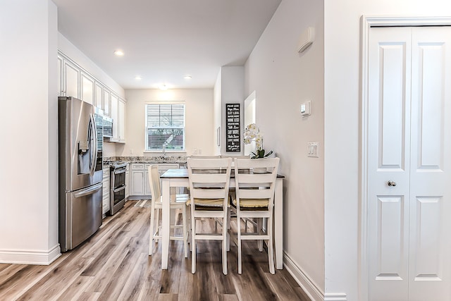 587 Anne Ave, Brighton, MI 48116 - kitchen with white cabinetry, baseboards, light wood-type flooring, and appliances with stainless steel finishes