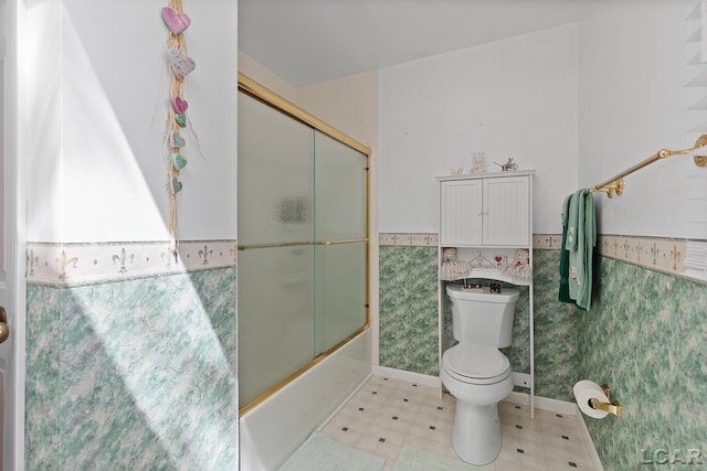 1402 Westhaven Blvd, Tecumseh, MI 49286 - bathroom featuring a wainscoted wall, toilet, tile patterned floors, bath / shower combo with glass door, and tile walls
