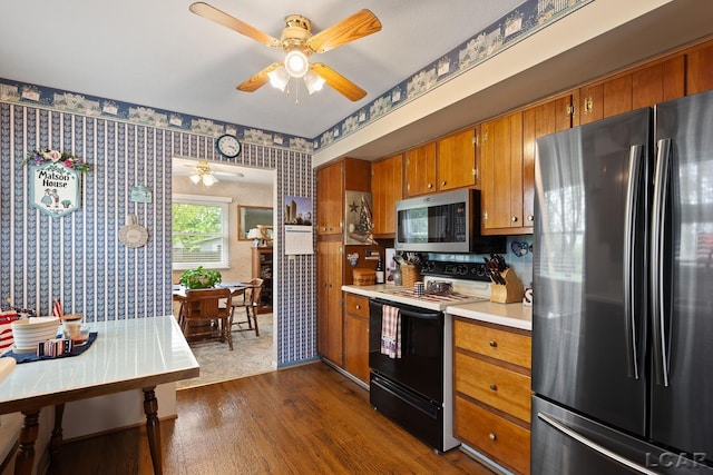 1402 Westhaven Blvd, Tecumseh, MI 49286 - kitchen featuring freestanding refrigerator, stainless steel microwave, black electric range oven, wallpapered walls, and brown cabinetry