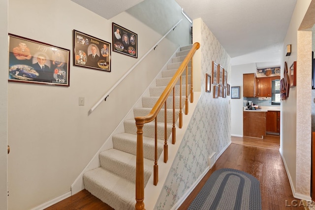 1402 Westhaven Blvd, Tecumseh, MI 49286 - stairway with wood finished floors, wallpapered walls, and baseboards