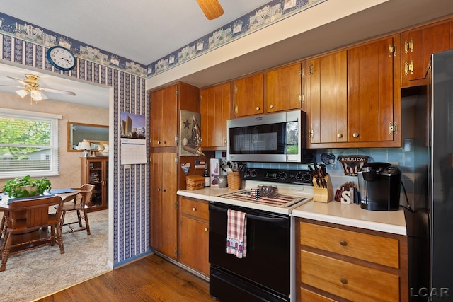 1402 Westhaven Blvd, Tecumseh, MI 49286 - kitchen with stainless steel microwave, electric stove, ceiling fan, wallpapered walls, and brown cabinetry