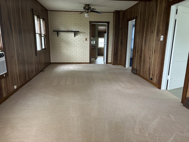 unfurnished room featuring wooden walls, carpet floors, ceiling fan, and baseboards