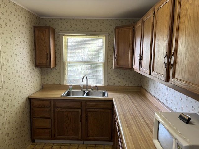 kitchen with light countertops, wallpapered walls, and a sink