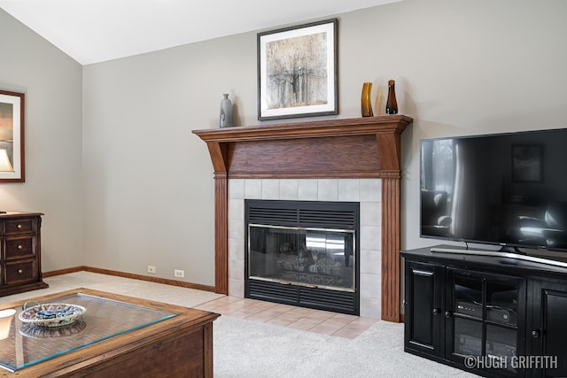 carpeted living room featuring baseboards, lofted ceiling, and a tiled fireplace