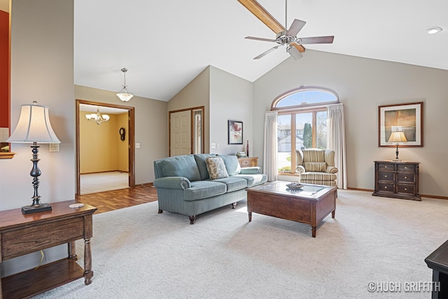 living room with light colored carpet, ceiling fan with notable chandelier, high vaulted ceiling, and baseboards