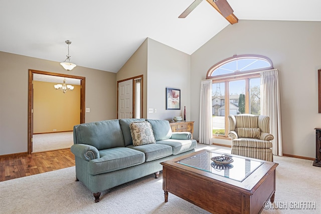living area featuring ceiling fan with notable chandelier, high vaulted ceiling, light carpet, beamed ceiling, and baseboards