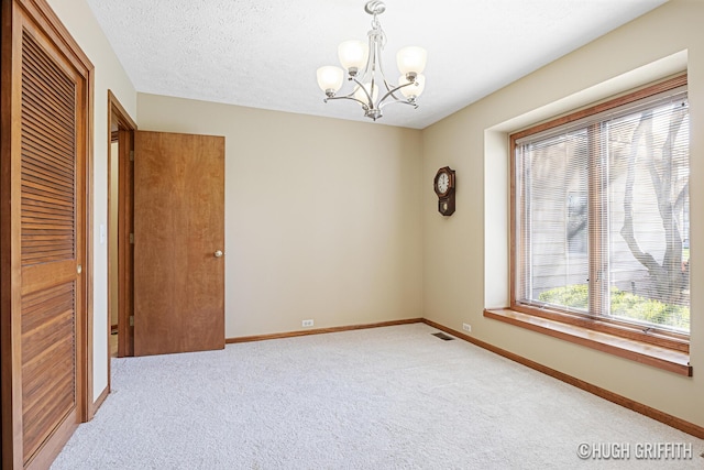 unfurnished room featuring carpet, a notable chandelier, baseboards, and visible vents