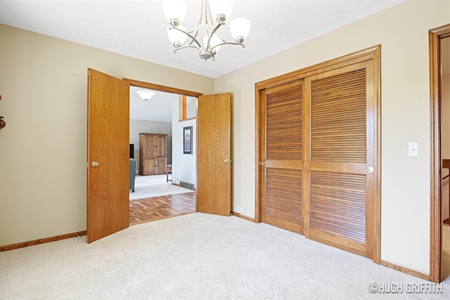unfurnished bedroom featuring an inviting chandelier, a closet, baseboards, and carpet