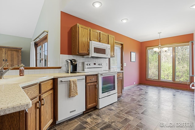 kitchen with white appliances, a healthy amount of sunlight, a chandelier, and a sink