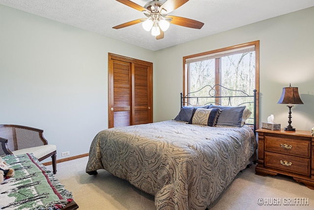 bedroom featuring light colored carpet, a closet, ceiling fan, and baseboards